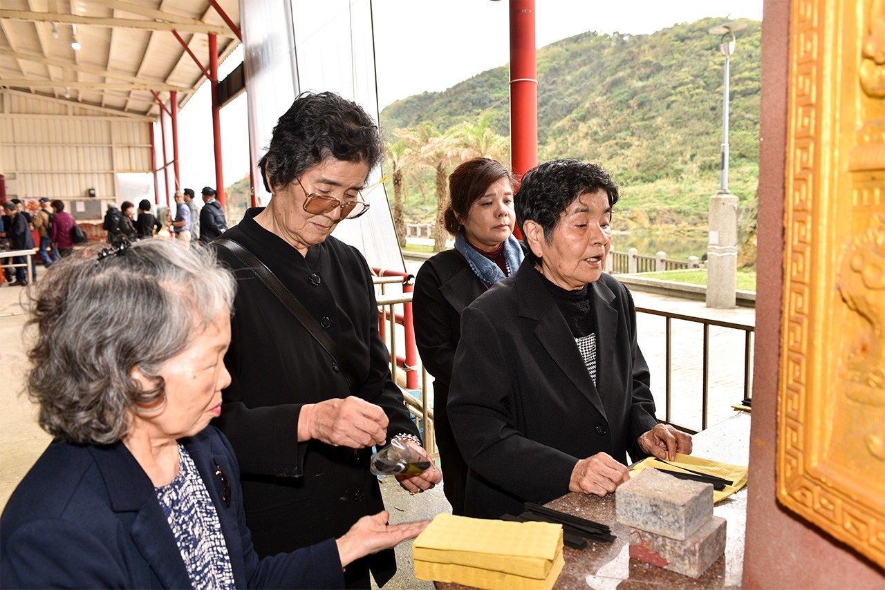 沖縄独特の黒い線香や黄色い紙銭で供養を行う遺族ら＝2018年3月1日、台湾基隆市（筆者撮影）