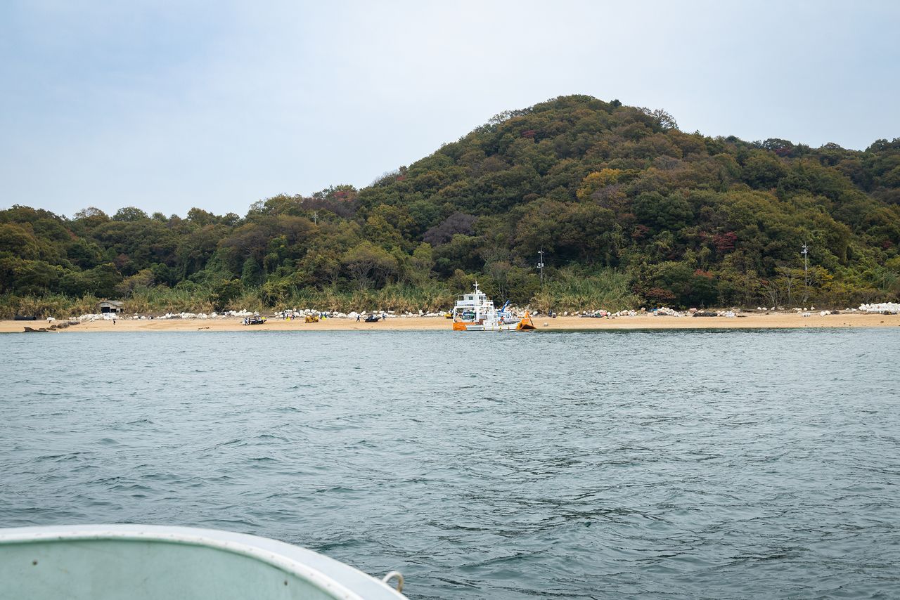 船から見た長浦海岸。美しい砂浜の奥に、白いフロートが延々と並ぶ