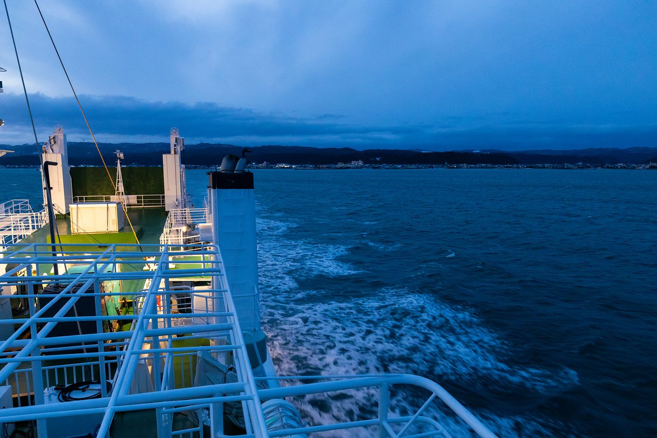 日没と同時に飯田港を出発した船から。街の明かりがほとんどともっていないことで、被害の大きさを改めて実感させられる