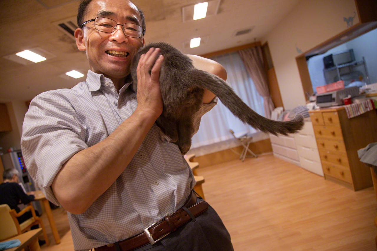 ロシアンブルーの保護猫アオをヒョイと抱き上げる施設長の若山。ホームの動物たちの頼れるボスだ