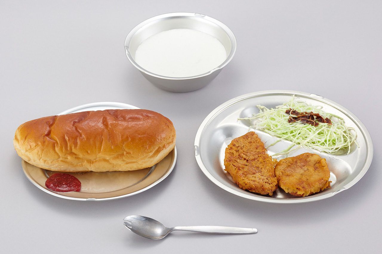 1952(昭和27)年ごろの学校給食。コッペパン、脱脂粉乳のミルク、クジラの竜田揚げ(独立行政法人日本スポーツ振興センター提供)