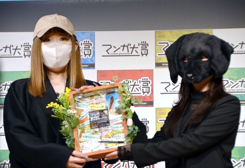 書店員らが選ぶ「マンガ大賞2025」で大賞となり、昨年の受賞者の泥ノ田犬彦さん(右)から記念品を受け取る『ありす、宇宙までも』の著者、売野機子さん(共同)