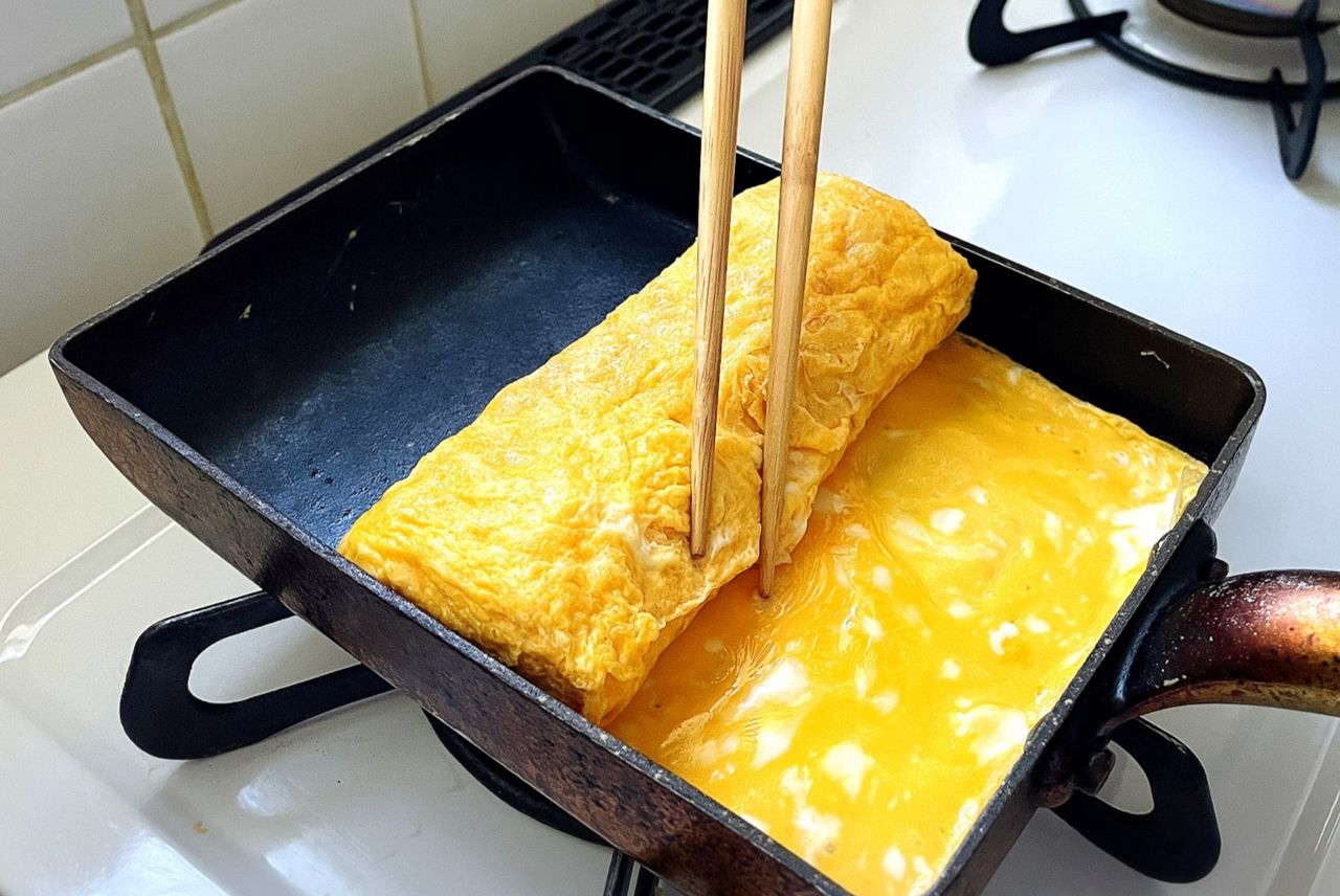 溶いた卵を数回に分けて流し入れ、折りたたむように巻く(フォトAC)