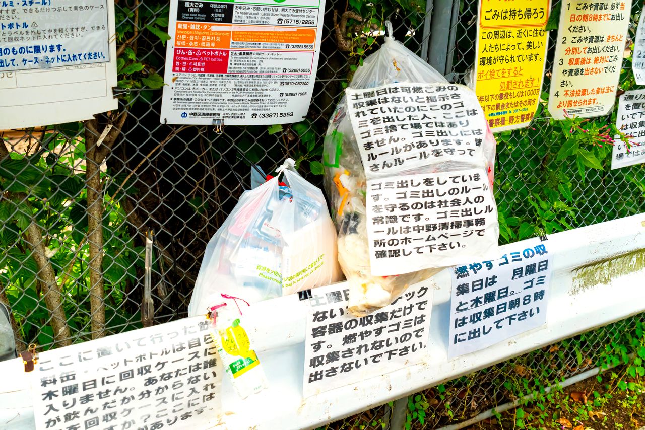 ごみの分別を呼び掛ける張り紙が並ぶごみ集積場(PIXTA)