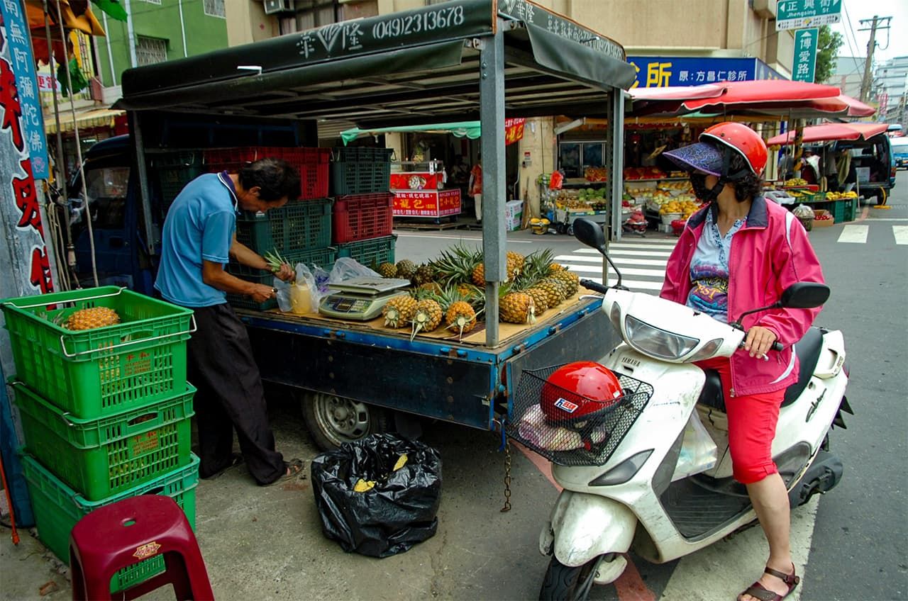 パインを荷台に載せたトラックを停め、路上で売り買いをする台湾の人たち＝2013年7月20日、台湾彰化県員林鎮、松田撮影