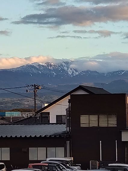 一時の晴れ間に山肌が白く染まった月山を望む＝18日午後4時半ごろ、鶴岡市切添町