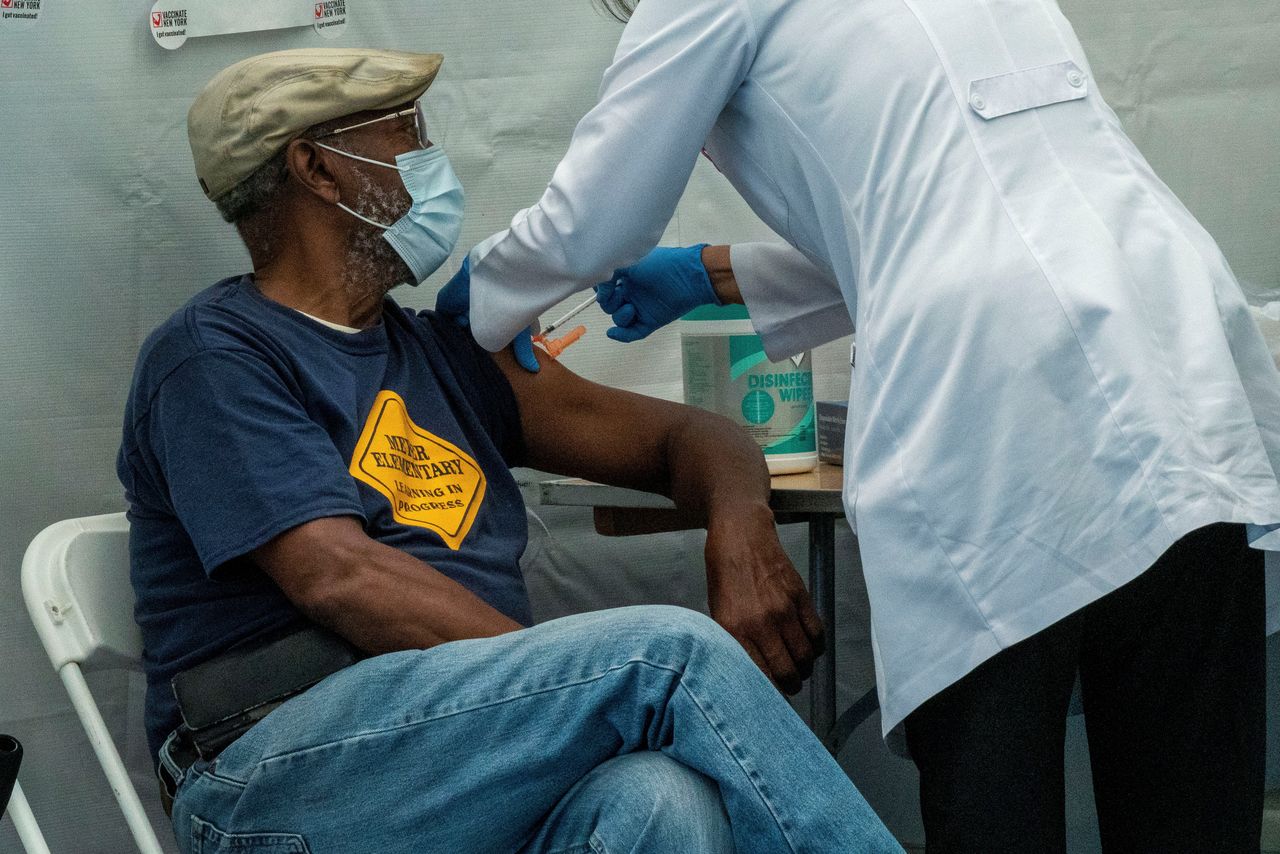 １０月２４日、ロイターの集計によると、新型コロナウイルスの感染者は世界全体で２億４３６５万人を超え、死者は５１８万０４８６人となった。写真は９月、ニューヨークでワクチン接種を受ける人（２０２１年　ロイター/David 