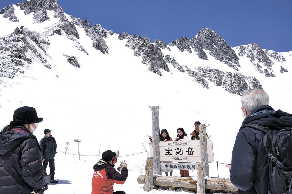 雪が残る山を背に記念写真を撮る観光客ら＝駒ケ岳ロープウェイ千畳敷駅周辺