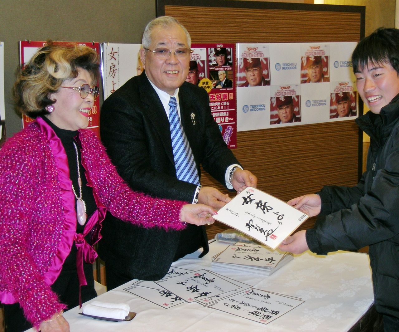 握手会でファンに色紙を渡す楽天監督時代の野村克也さん(中央)と沙知代夫人(左)=2009年1月29日、宮城・仙台市内のホテル(時事)