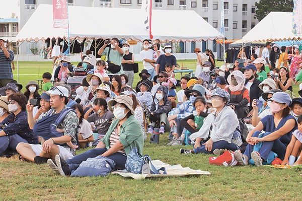 多くの観客が芝に腰掛け、石垣風のハワイアンな雰囲気を味わった＝2日午後、舟蔵公園特設ステージ