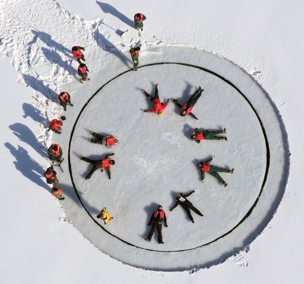 湖の氷を円形にくりぬき回転させて楽しむ「アイスカルーセル」を体験する関係者（中札内村の札内川ダムで。ドローンで撮影）