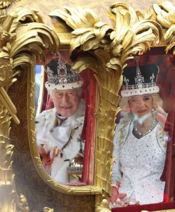 戴冠式を終え、王室伝統の馬車「ゴールド・ステート・コーチ」でバッキンガム宮殿に戻るチャールズ英国王（左）とカミラ王妃＝6日、ロンドン（共同）