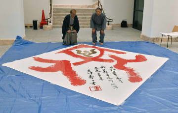 文化庁の京都移転を記念した書道パフォーマンスで、「文化」の文字を揮毫した吉川壽一さん。左は門川大作市長＝7日、京都市役所
