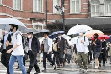 雨の中、マスク姿で通勤する人たち＝8日午前、JR東京駅前