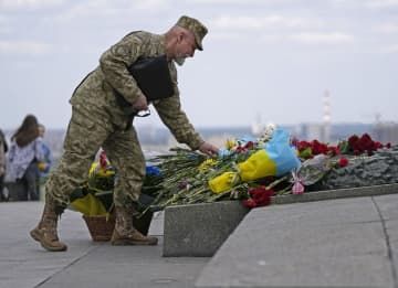 首都キーウにある無名戦士の記念碑に花を手向ける軍人のピョートル・ニジェールスキーさん＝8日（共同）