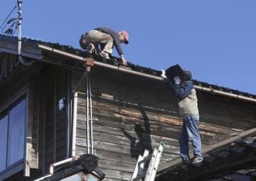 地震で被害を受けた住宅屋根の修復作業に追われる住民ら＝9日午後、石川県珠洲市