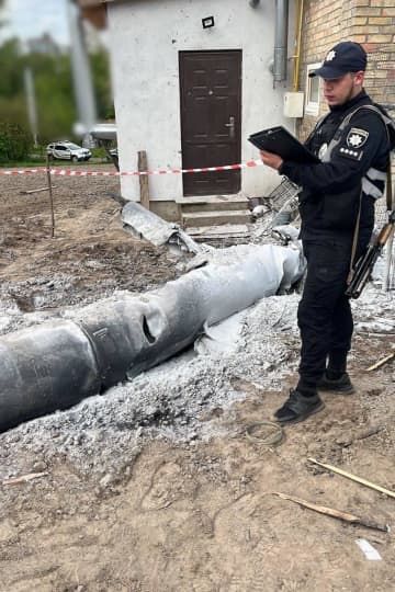9日、ウクライナ・キーウ州の民家の敷地で、迎撃された巡航ミサイルの残骸を調べる警察官（ウクライナ警察当局提供・ロイター＝共同）