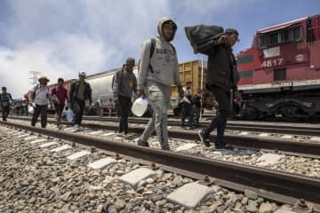 10日、メキシコ・シウダフアレス近郊で、貨物列車を降り米国との国境に向かう移民（ゲッティ＝共同）
