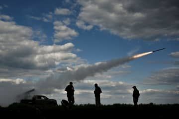 12日、ウクライナ南部ザポロジエ州でロシア軍に向けて多連装ロケット砲を発射するウクライナ軍兵士ら（ロイター＝共同）