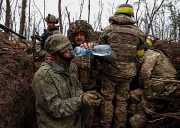バフムト前線で捕らえたロシア兵に水を与えるウクライナ兵士＝ドネツク州、11日（ロイター＝共同）