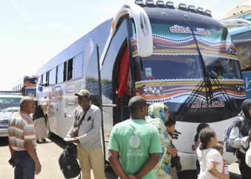 エジプト南部アスワン郊外のバス停で、スーダンから国境を越えて来たバスを降りる人々＝14日（共同）