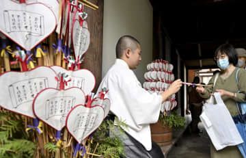 奈良市の唐招提寺で、うちわを手渡す僧侶＝19日午後