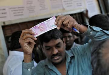 2千ルピー紙幣を持つ男性＝2016年11月、インド・ムンバイ（ロイター＝共同）