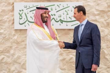 サウジアラビアのムハンマド皇太子（左）と握手するシリアのアサド大統領＝19日、サウジ西部ジッダ（ロイター＝共同）