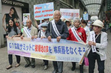 横断幕を掲げ、広島市内を練り歩く被爆者や市民団体メンバーら＝20日午前