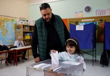 21日、ギリシャ・アテネで投票する親子（ロイター＝共同）