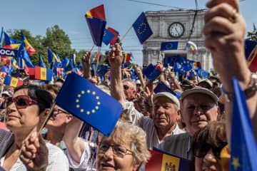 21日、モルドバの首都キシナウで行われた欧州連合（EU）加盟実現を求める集会で国旗や欧州旗を振る参加者（ゲッティ＝共同）