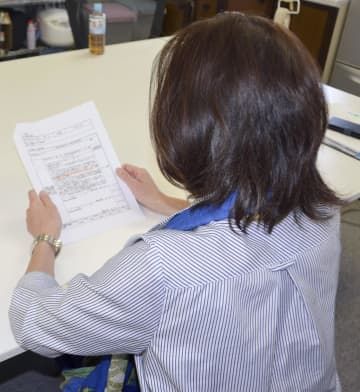 労災認定の文書を見つめる女性幹部＝4月、東京都世田谷区
