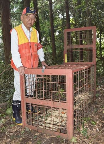 佐賀県猟友会多久支部の毛貫茂さんと、イノシシを捕獲するための箱わな＝22日、佐賀県多久市