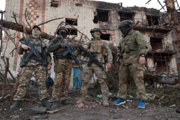 ウクライナ東部ドネツク州バフムトで、損壊した建物の前に立つロシア民間軍事会社「ワグネル」の戦闘員＝4月10日（タス＝共同）