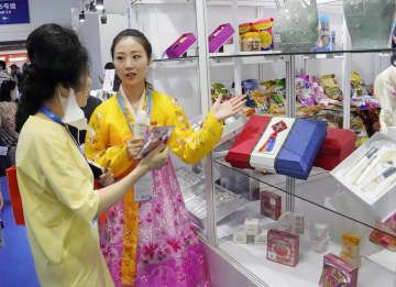 23日、中国吉林省長春市で開幕した「中国・北東アジア博覧会」で北朝鮮の化粧品の説明をする担当者の女性（右）（共同）