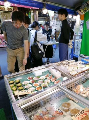 東京・築地場外市場の鮮魚店で品定めをする買い物客＝25日午前