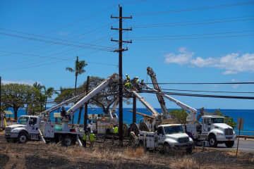 米マウイ島ラハイナで電線を修理する作業員ら＝15日（ロイター＝共同）