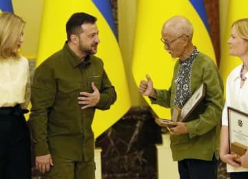 ウクライナのゼレンスキー大統領（左から2人目）から賞を受ける邦人ボランティアの土子文則さん＝23日、キーウ（共同）