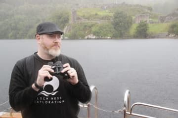 英北部ネス湖で、ネッシーの大捜索を控え、船上から湖面を眺めるアラン・マッケーナさん＝25日（共同）