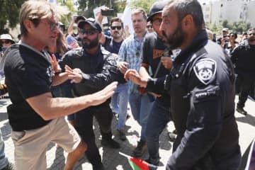 ヨルダン川西岸のユダヤ人入植地キリヤトアルバで、警察官ともみ合うデモ参加者（左）＝25日（共同）