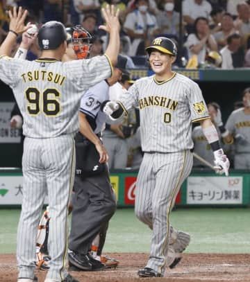7回、満塁本塁打を放ち、コーチに迎えられる阪神・木浪（右）＝東京ドーム