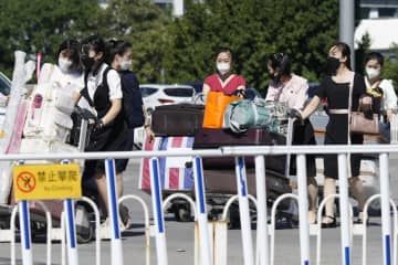 北京の北朝鮮大使館が用意したとみられる車両から多くの荷物を携行して北京首都国際空港のターミナルに向かう女性ら＝22日（共同）