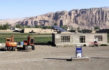 アフガニスタンのバーミヤン遺跡を望む地区に建設されているガソリンスタンド。奥に見える崖のくぼみが遺跡の西大仏＝5月（共同）