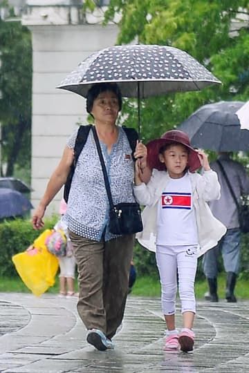 平壌市内を傘を差して歩く市民＝28日（共同）