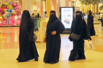 伝統衣装「アバヤ」を身に着け、ショッピングモールで買い物をする女性＝2017年11月、サウジアラビア・ジッダ（共同）