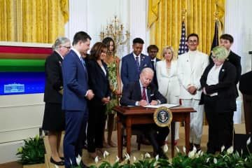 昨年6月、米ホワイトハウスで、LGBTQなど性的少数者を擁護するための大統領令に署名するバイデン大統領（中央）（ロイター＝共同）