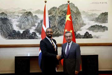 30日、北京で中国の王毅共産党政治局員兼外相（右）と握手するクレバリー英外相（ロイター＝共同）