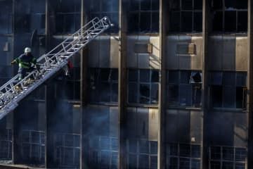 31日、南アフリカ・ヨハネスブルクの火災で作業をする消防士（ロイター＝共同）