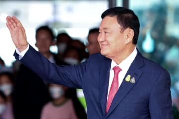 タイ・バンコクの空港で手を振るタクシン元首相＝8月22日（ロイター＝共同）
