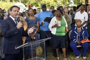 米フロリダ州ジャクソンビルでの追悼式典で、演説するデサンティス知事（左端）＝8月27日（AP＝共同）